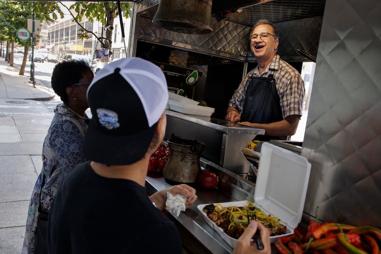 Konstadinos “Gus” Christis laughs as he talks with regular customer Chris Cahill at the Octopus Cart on 20th Street near Market Street in Philadelphia.