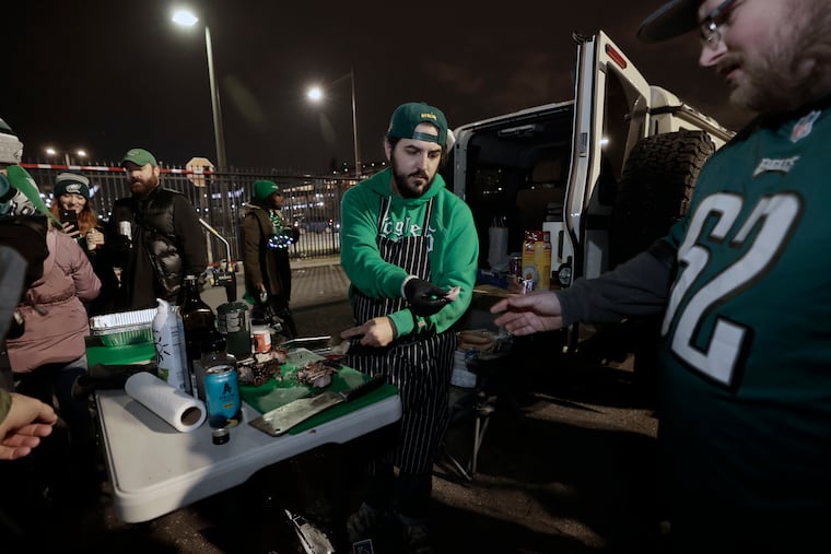 Dylan Marck, of Newark, Del., hands out some Iberico pork chops in Lot M during a recent Eagles tailgate.