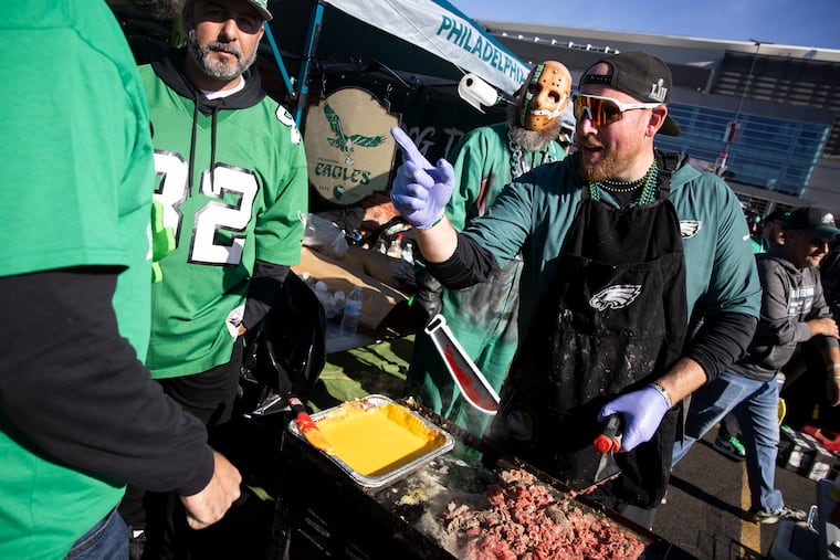 Sean Holden works on cheesesteaks as The Philly Slasher, Karl Phelps, looks on while tailgating at Lincoln Financial Field on Sunday, Nov. 3, 2024 in Philadelphia.